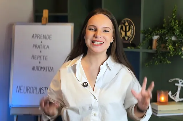Luana Fontana Petri ensinando, ao lado do quadro com as etapas aprende, pratica, repete, automatiza