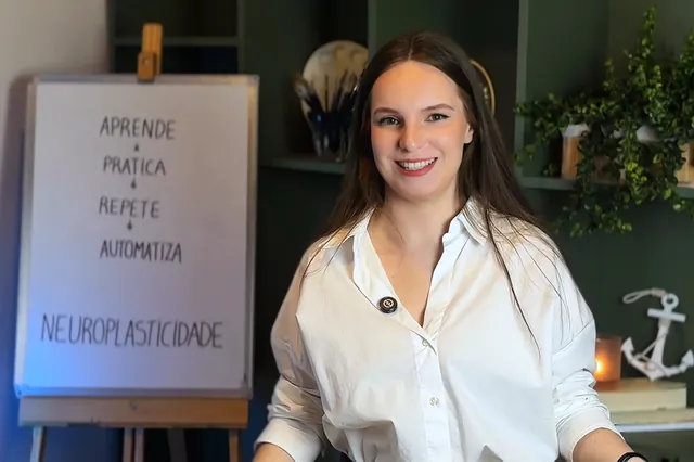 Luana Fontana Petri sorrindo, de camisa branca, ao lado do quadro